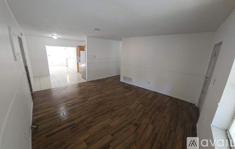 A spacious room with wooden flooring and white walls.