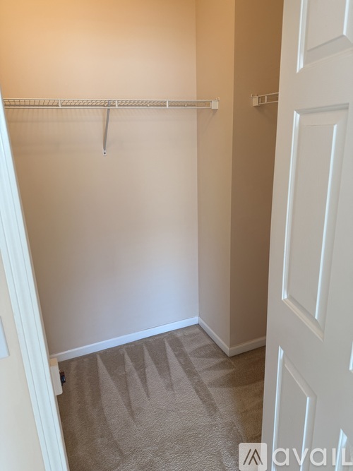 A white door is on the right side of a room with a carpeted floor.