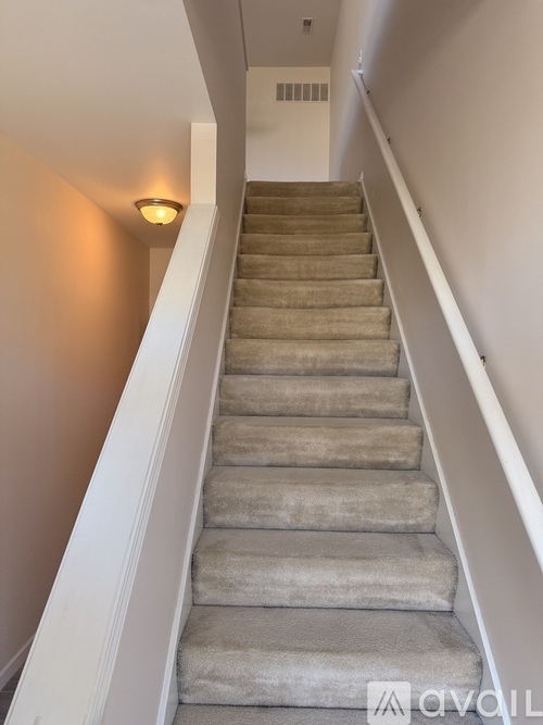 A staircase with beige carpeted steps and white railings.
