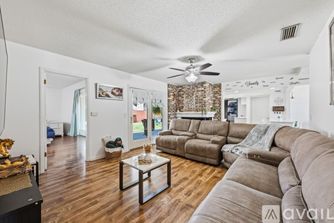 A living room with a brown couch and a glass coffee table.