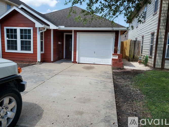 A red house with a white garage door and a white car parked in front.