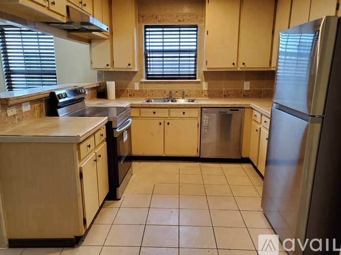 A kitchen with wooden cabinets and a stainless steel refrigerator.
