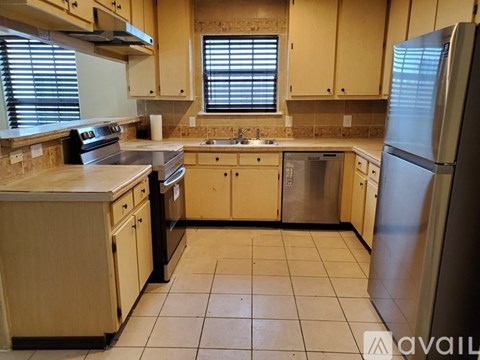 A kitchen with wooden cabinets and a stainless steel refrigerator.