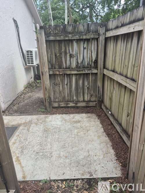 A wooden fence with a gate is in front of a white wall.
