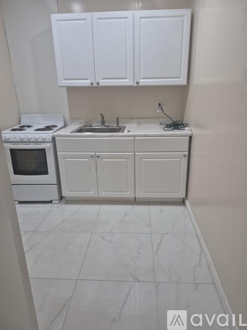 A kitchen with white cabinets and a white stove top oven.