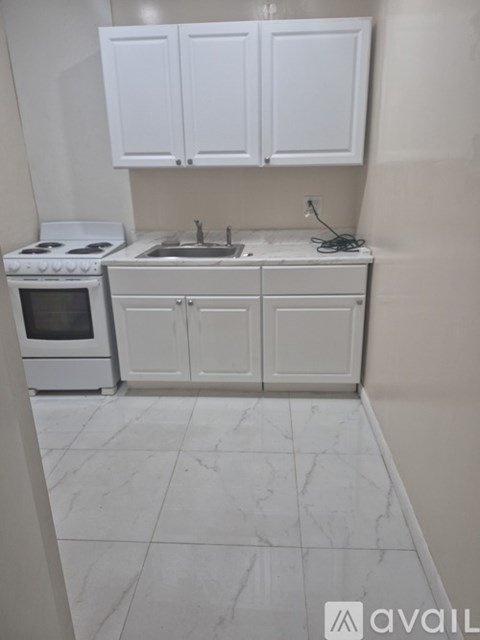 A kitchen with white cabinets and a white stove top oven.