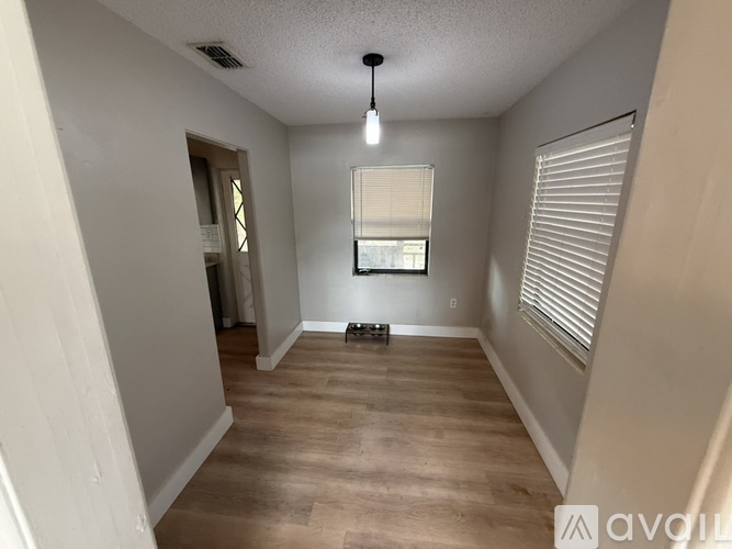 A room with wooden flooring and a window with blinds.