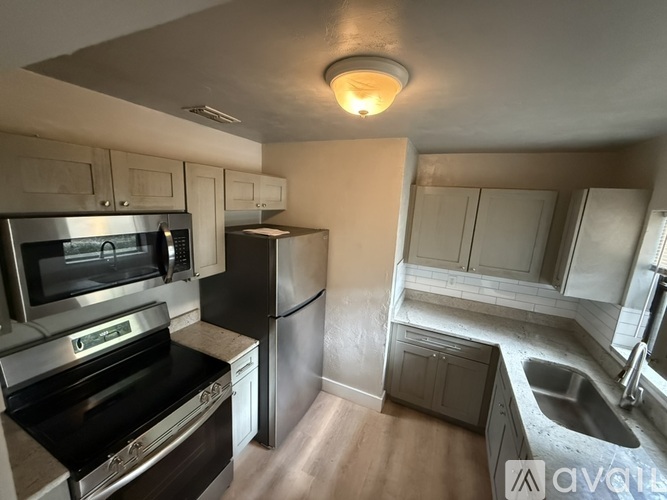 A kitchen with a stove, oven, refrigerator, and sink.