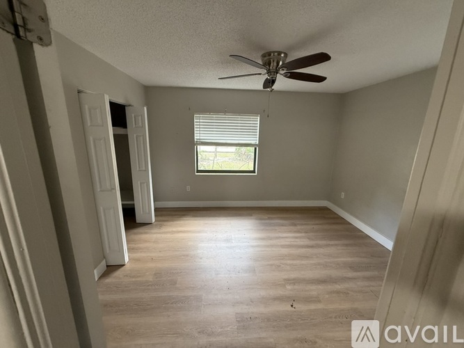A room with a ceiling fan and a window with blinds.