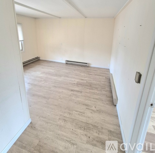 A room with wooden flooring and white walls.