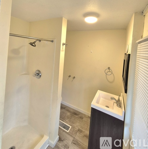 A bathroom with a shower, sink, and towel rack.