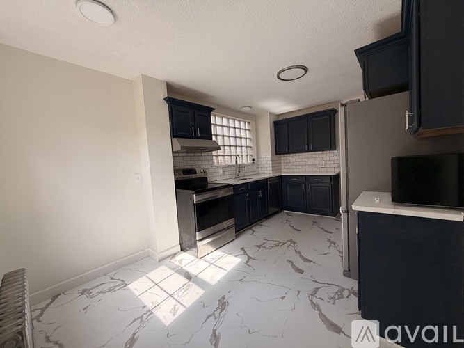 A kitchen with black cabinets and a marble floor.