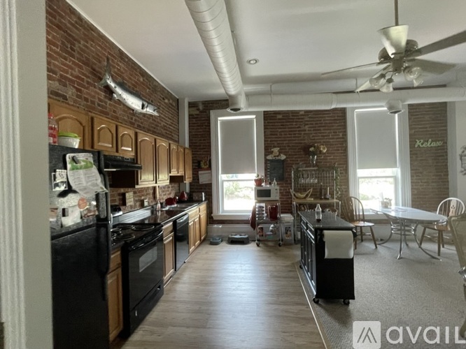 A kitchen with a brick wall and wooden floors.
