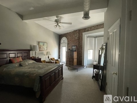 A bedroom with a large bed and a ceiling fan.