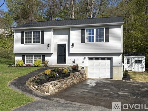 A two-story house with a garage and a stone wall in front.