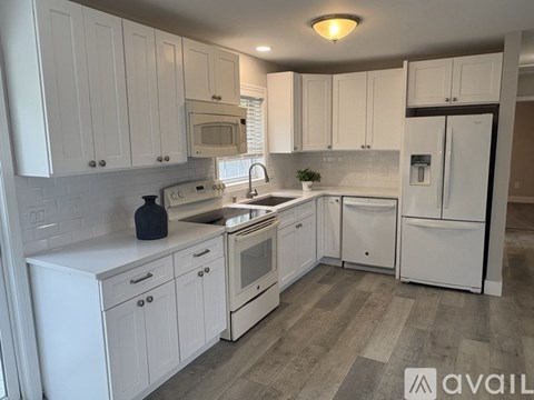 A kitchen with white cabinets and appliances.