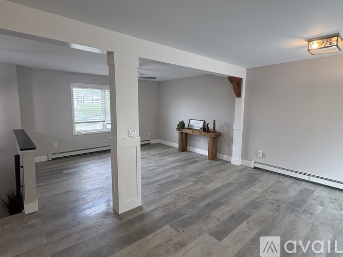 A spacious living room with a grey floor and white walls.