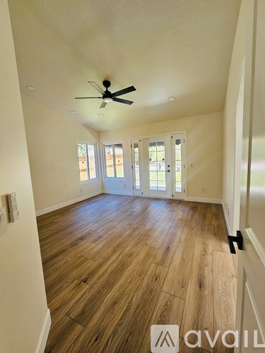 A room with a ceiling fan and sliding glass doors.