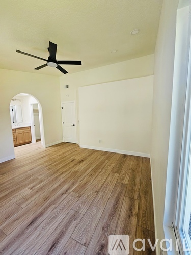 A room with a ceiling fan and wooden flooring.