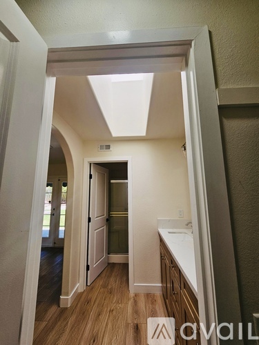 A long hallway with white walls and wood flooring.