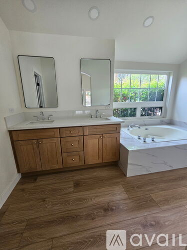 A bathroom with wooden floors and a large tub.
