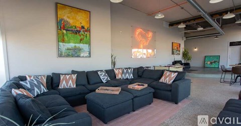 A living room with a large black sofa and a painting on the wall.