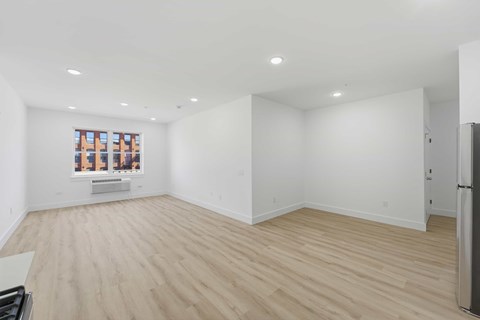 A spacious room with wooden flooring and white walls.