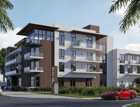 A red sports car is parked on the street in front of a modern apartment building.