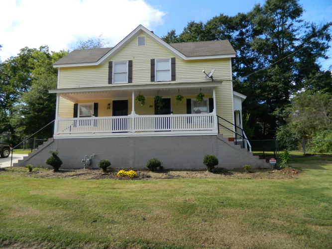 A yellow house with a grey front porch.