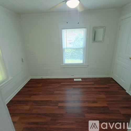 A room with wooden flooring and a window.
