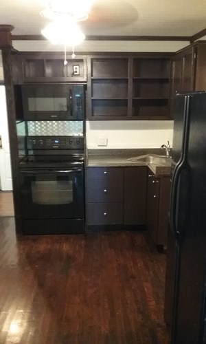 A kitchen with a black refrigerator and wooden cabinets.