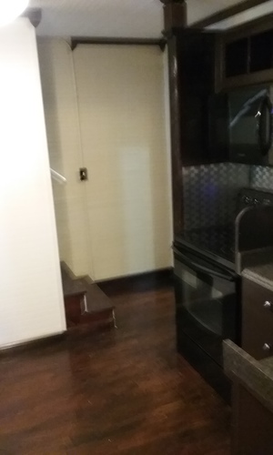 A kitchen with a black oven and wooden floors.