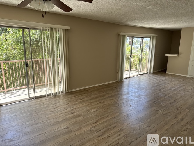 A room with wooden flooring and sliding glass doors leading to a balcony.