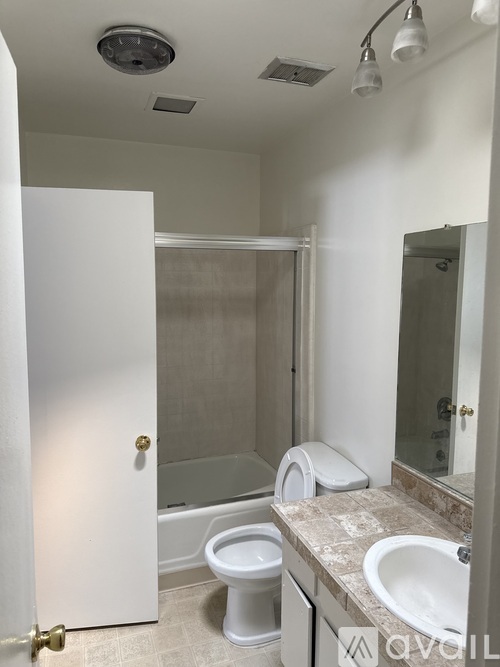 A white bathroom with a toilet, sink, and shower.
