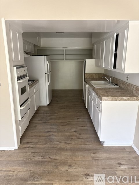 A kitchen with white cabinets and a wooden floor.