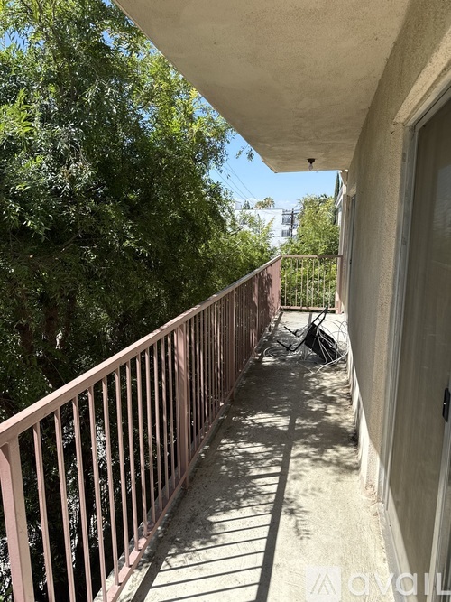 A balcony with a metal railing and a view of trees and a building in the background.