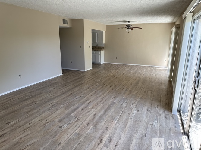 A spacious room with wooden flooring and a ceiling fan.
