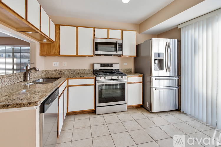 A kitchen with white cabinets and a granite countertop.
