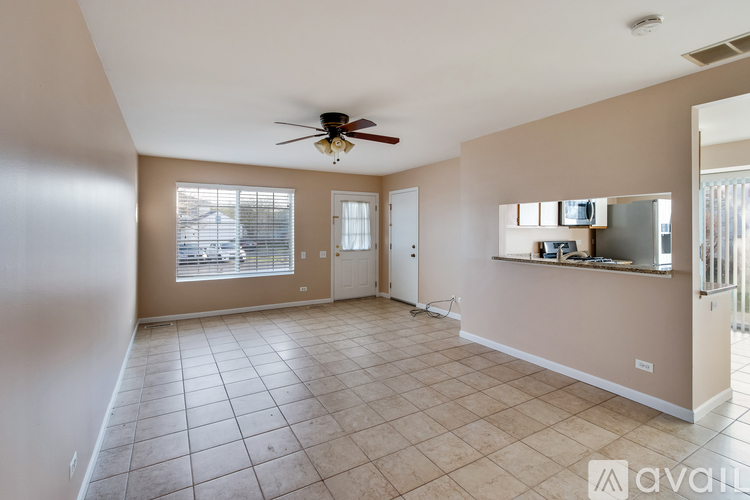 A spacious living room with a ceiling fan and tiled flooring.