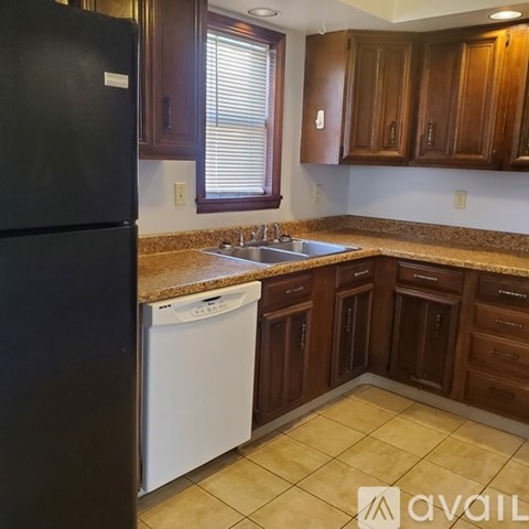 A kitchen with brown cabinets and a black refrigerator.