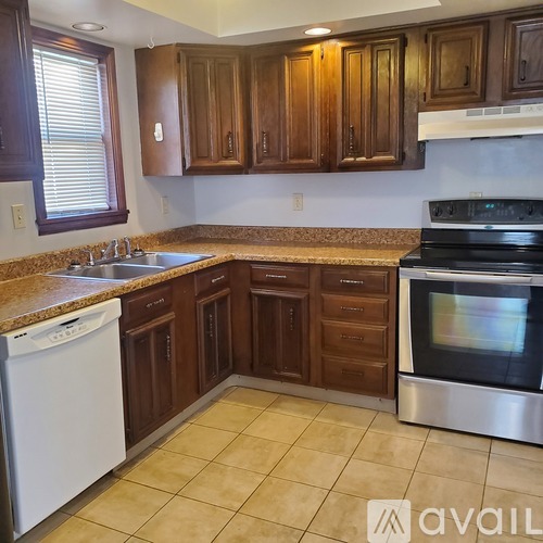 A kitchen with brown cabinets and a white dishwasher.
