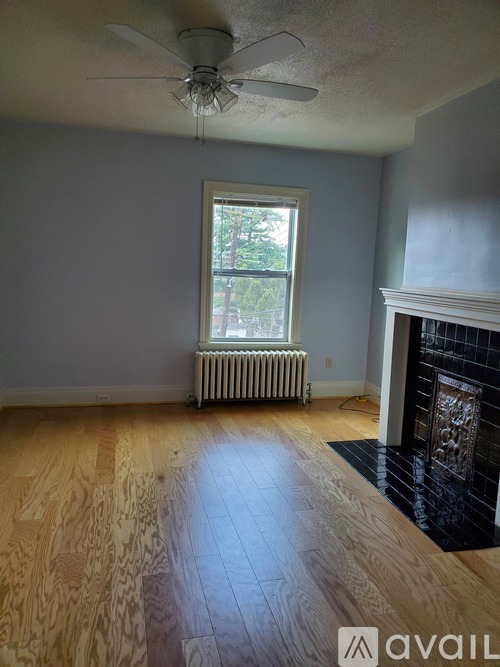 A room with a ceiling fan and a fireplace.