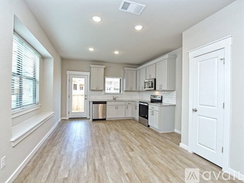 A kitchen with white cabinets and a wooden floor.