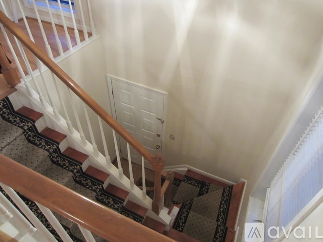 A staircase with a wooden handrail and a black and white patterned runner.