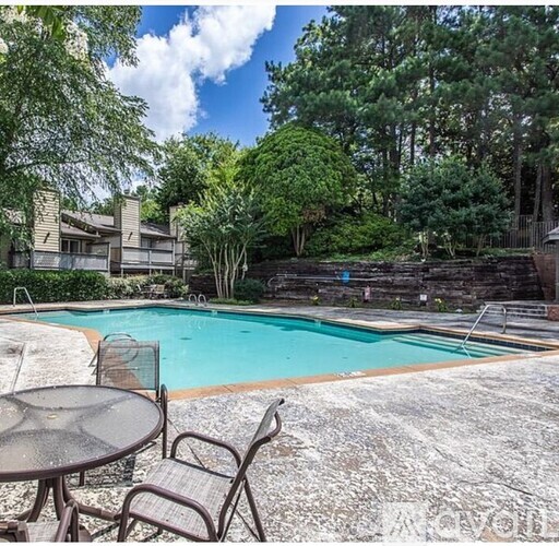 A pool surrounded by trees and a patio table.