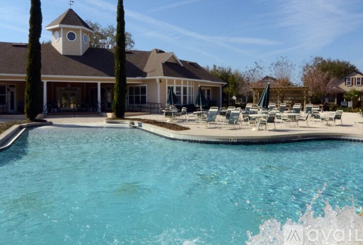 A large swimming pool in front of a house with a clock tower.