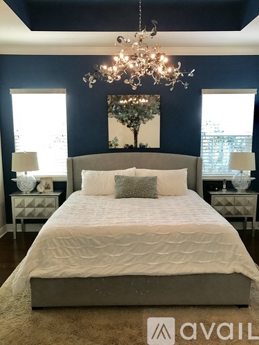 A bedroom with a large bed and a chandelier.