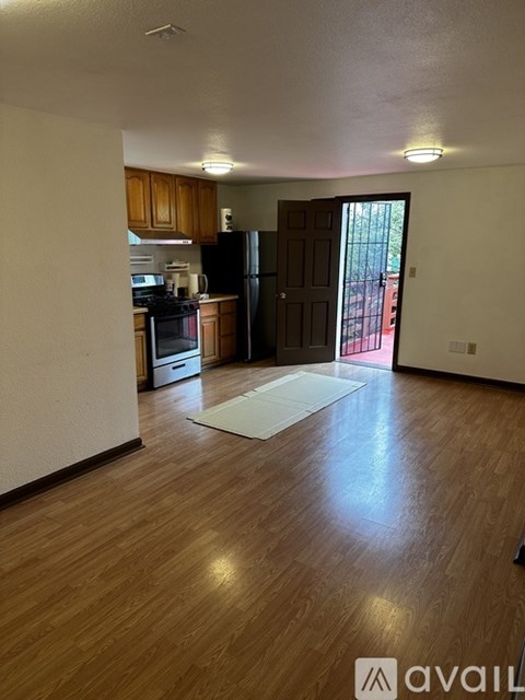 A kitchen with wooden cabinets and a black fridge is visible through a doorway.