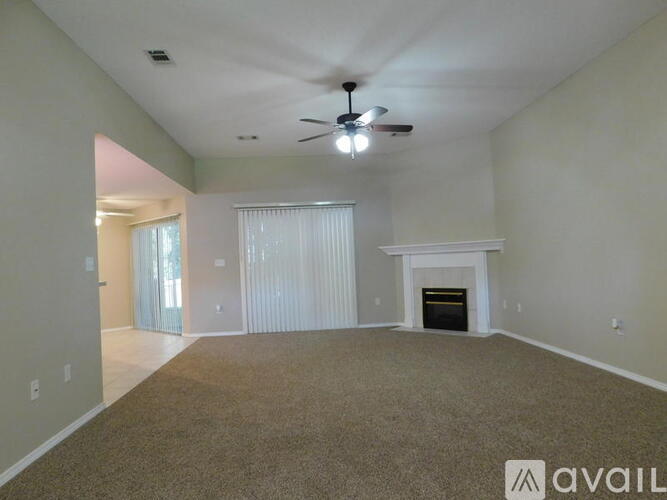 A spacious room with a carpeted floor and a ceiling fan.