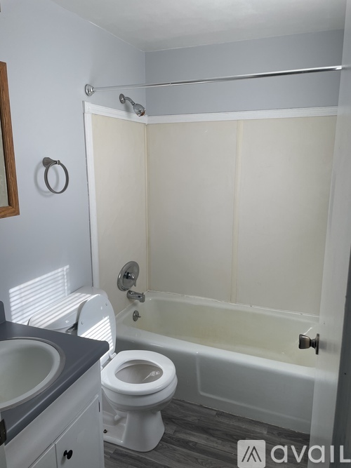 A white toilet is in a bathroom with a white tub.